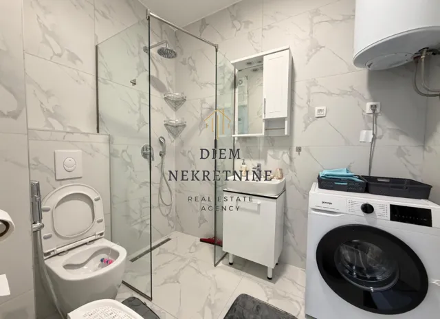 Modernly equipped bathroom with a walk-in shower and a washing machine.