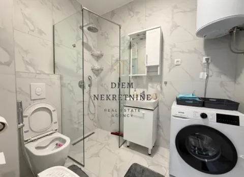 Modernly equipped bathroom with a walk-in shower and a washing machine. - image 11