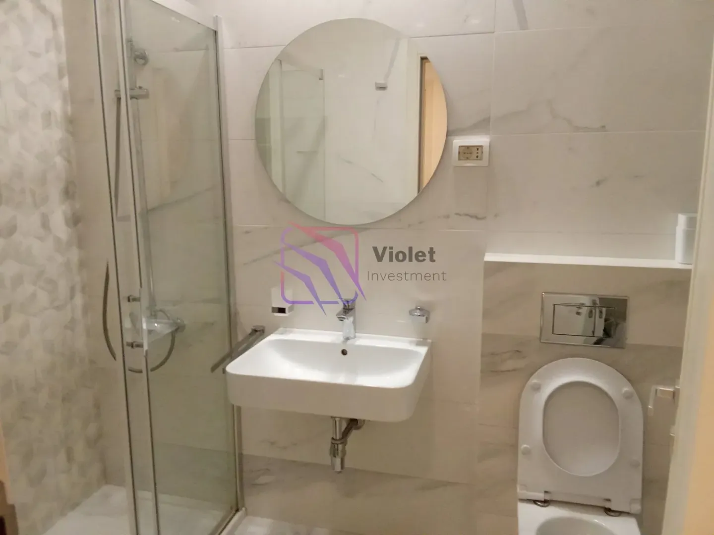 Modern bathroom with a walk-in shower, washbasin, and wall-hung toilet.