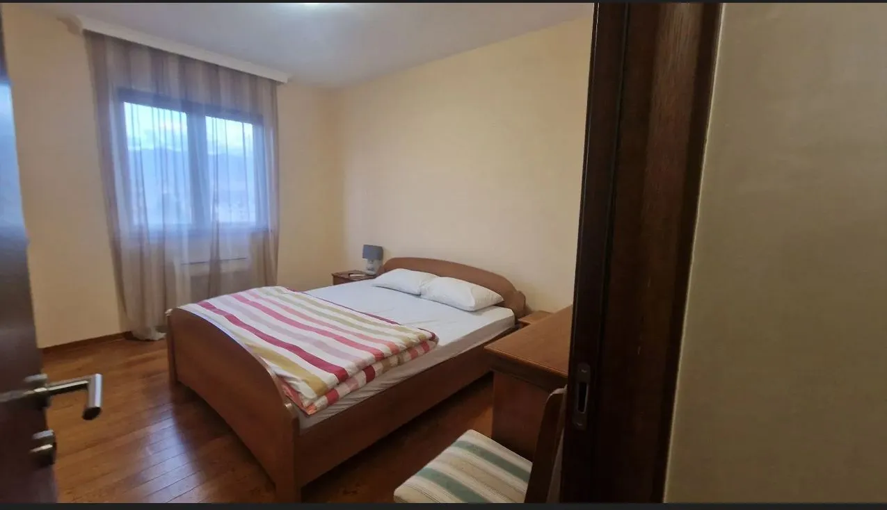 Bright bedroom with a double bed and wooden floor.