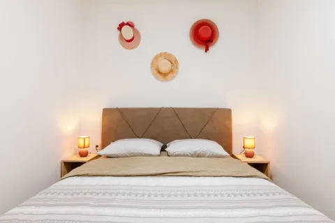 Bedroom with a double bed, bedside tables, and decorative hats on the wall. - image 2