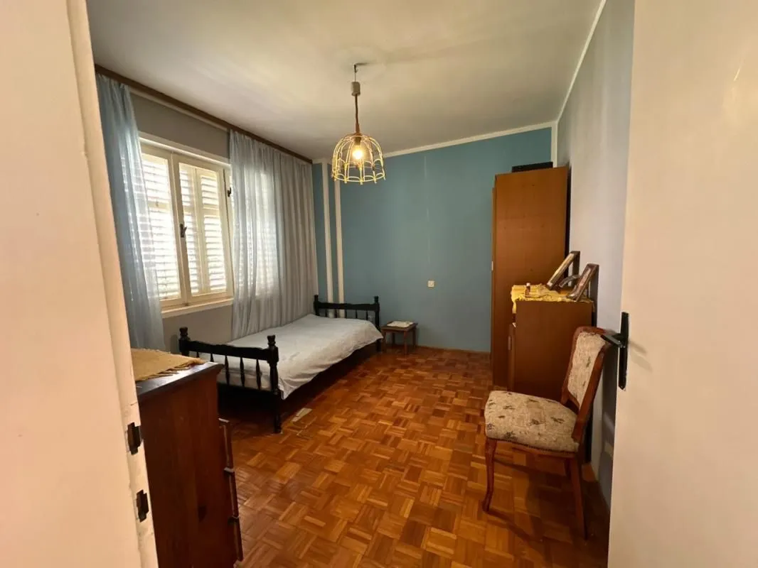 Furnished bedroom with a bed and wooden parquet flooring.