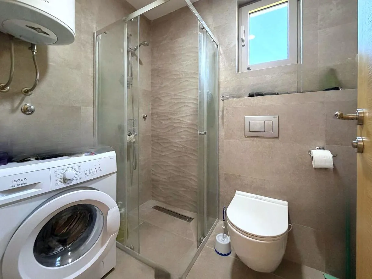 Moderne kupatilo sa tuš kabinom, wc šoljom i veš mašinom.