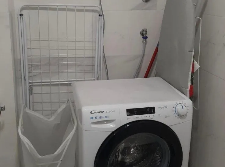 Bathroom with a washing machine and drying rack.