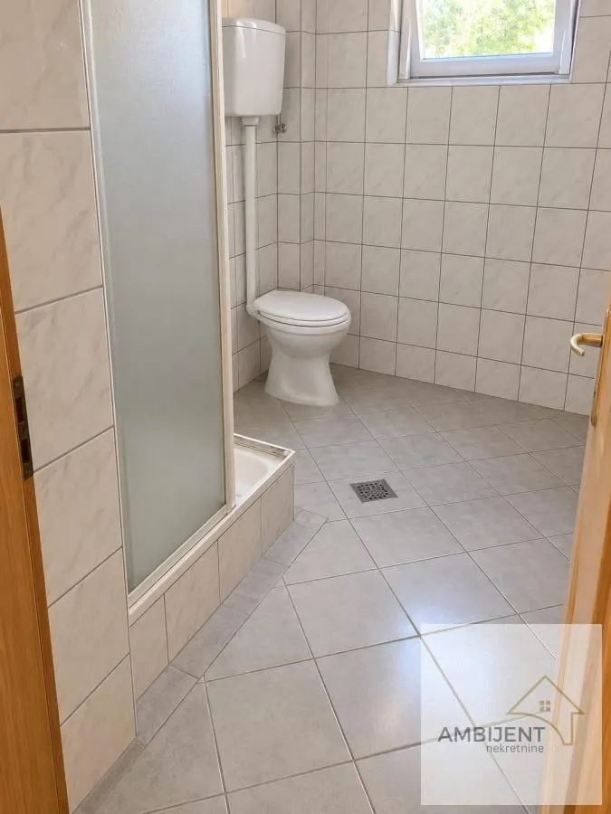 Kupatilo sa tuš kabinom, pločicama i sanitarijama.