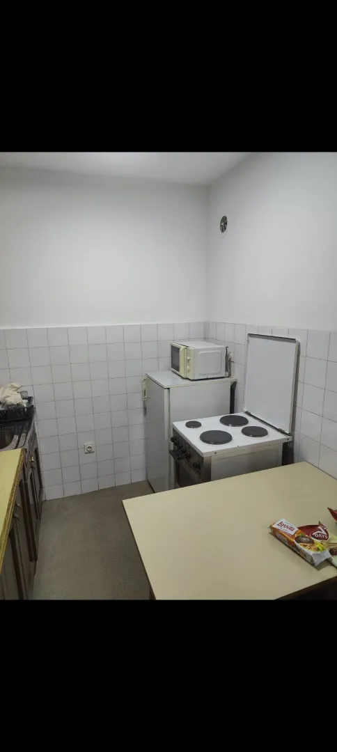 Manja kuhinja sa šporetom, frižiderom i radnim stolom.