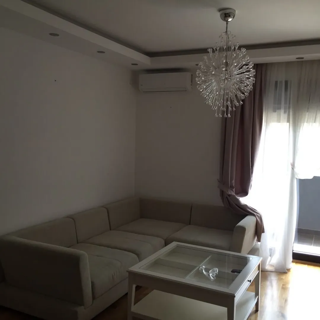 Bright living room featuring a sectional sofa, white coffee table, and a modern chandelier.