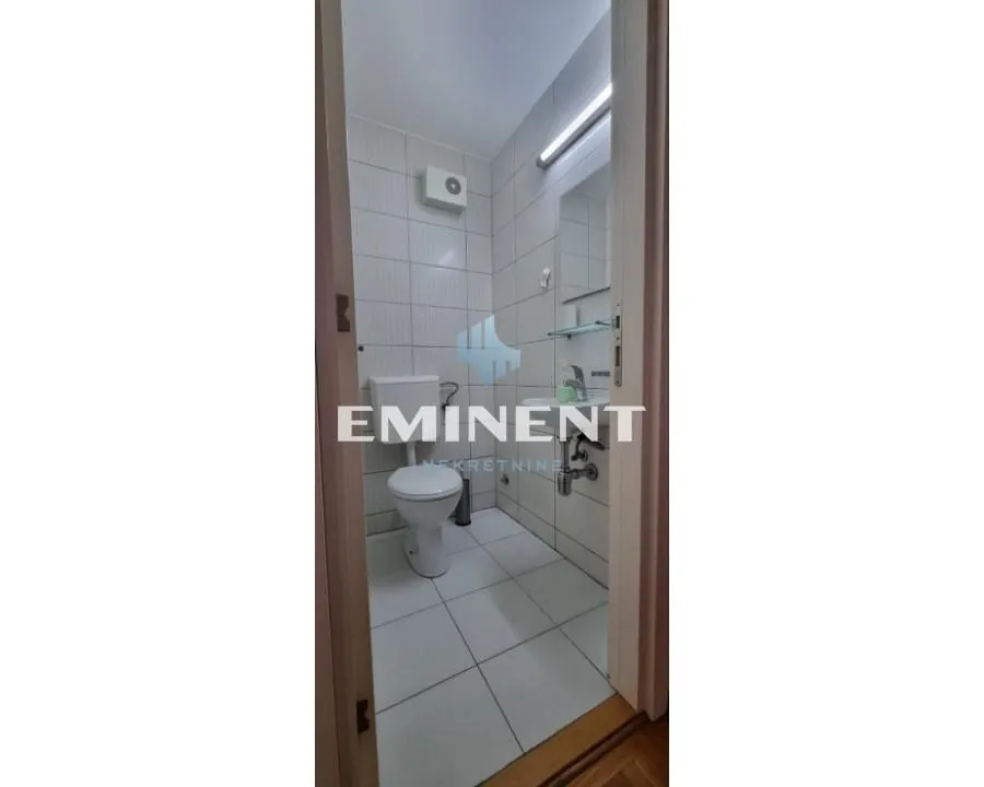 Small bathroom with white tiles, toilet, and washbasin.