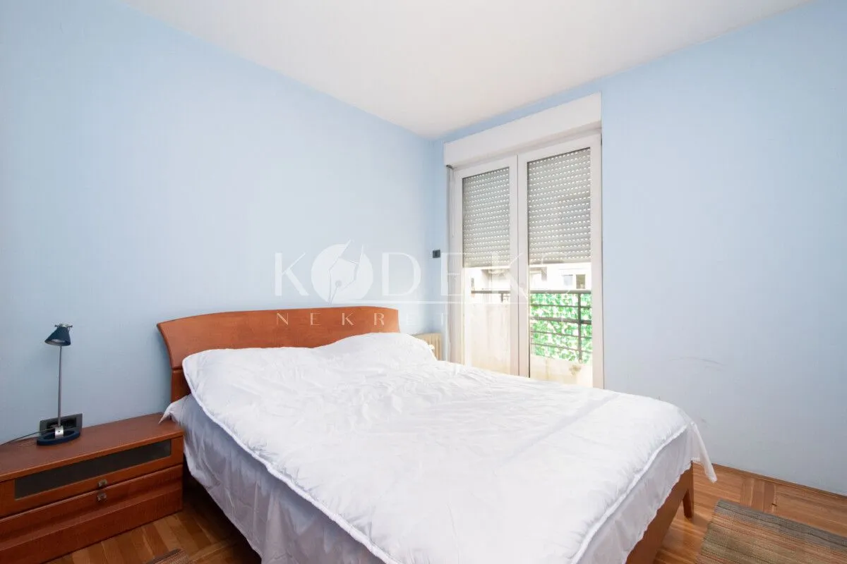 Spavaća soba sa bračnim krevetom, noćnim stočićem i izlazom na terasu.