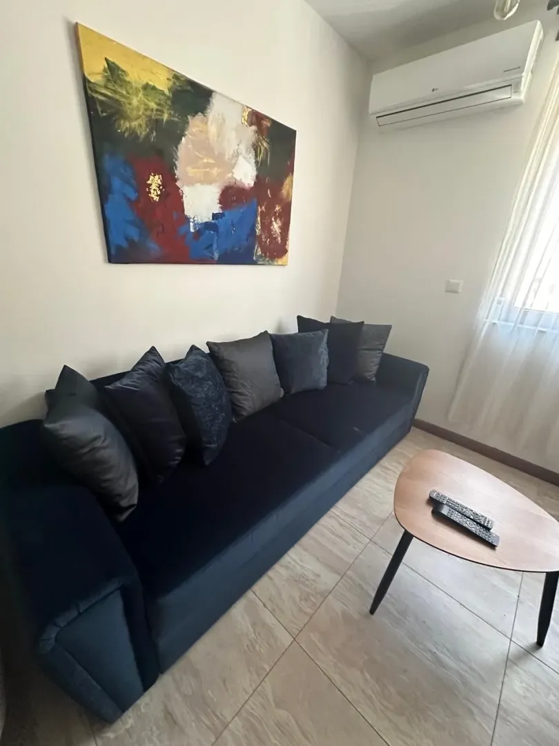 Living room with a dark sofa, coffee table, and an artwork on the wall.