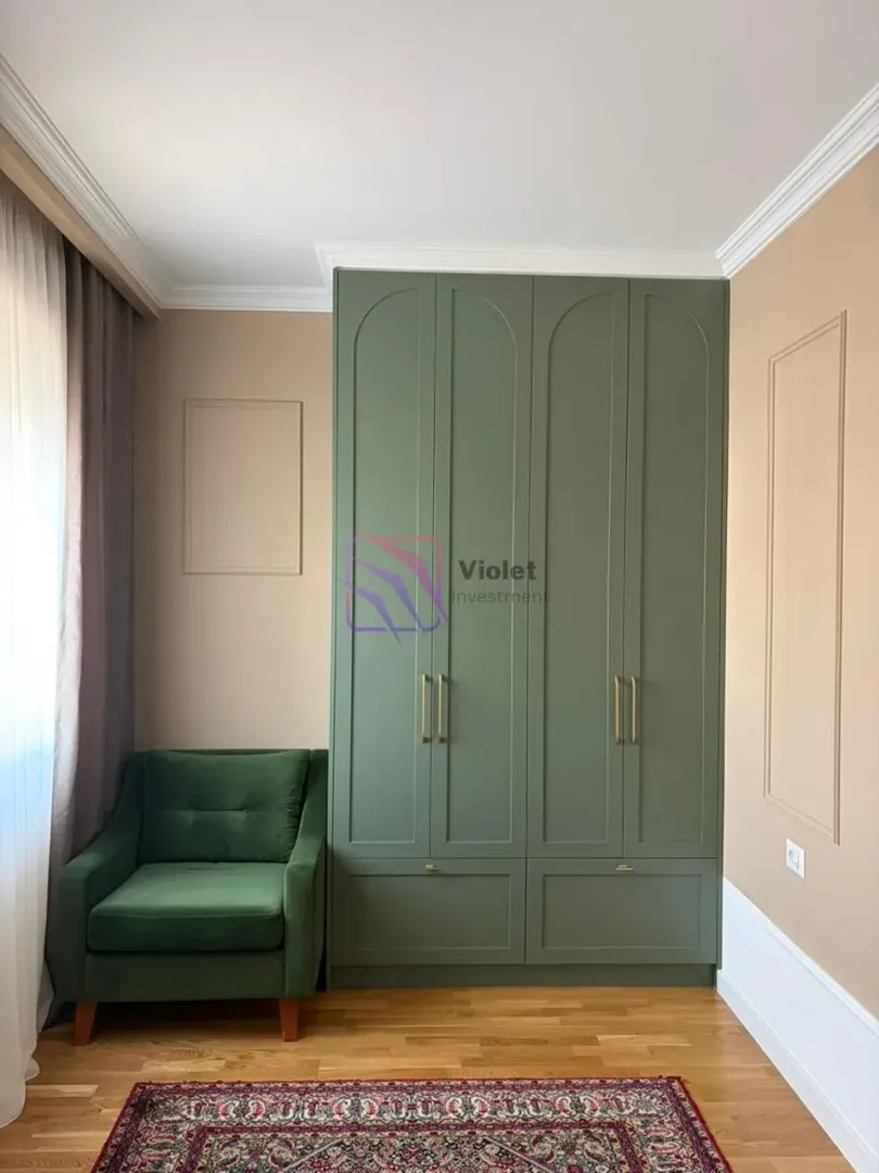 Spavaća soba sa velikim zelenim ormarom i foteljom.