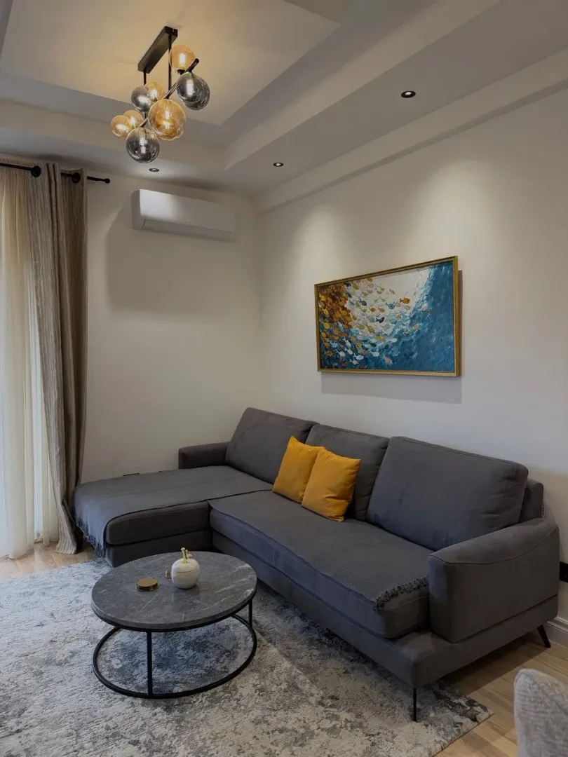 Living room with a sectional sofa, coffee table and decorative painting on the wall.
