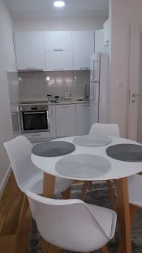 Trpezarijski sto sa stolicama ispred moderne bijele kuhinje. - image 10