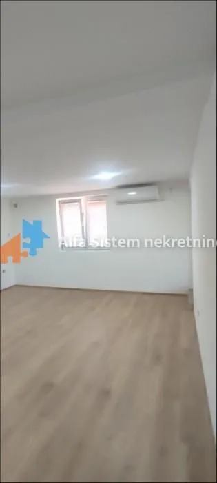 Empty bright room with laminate flooring, white walls, and an air conditioning unit.