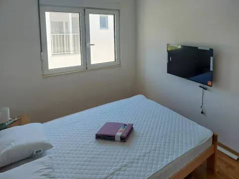 Spavaća soba sa krevetom, prozorom i zidnim televizorom. - image 10