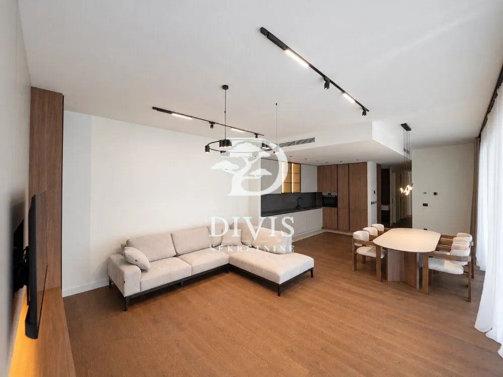Spacious living room with a sofa set, dining area, and kitchen in the background.