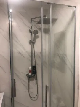 A modern shower cabin with glass doors and marble tiles. - image 12