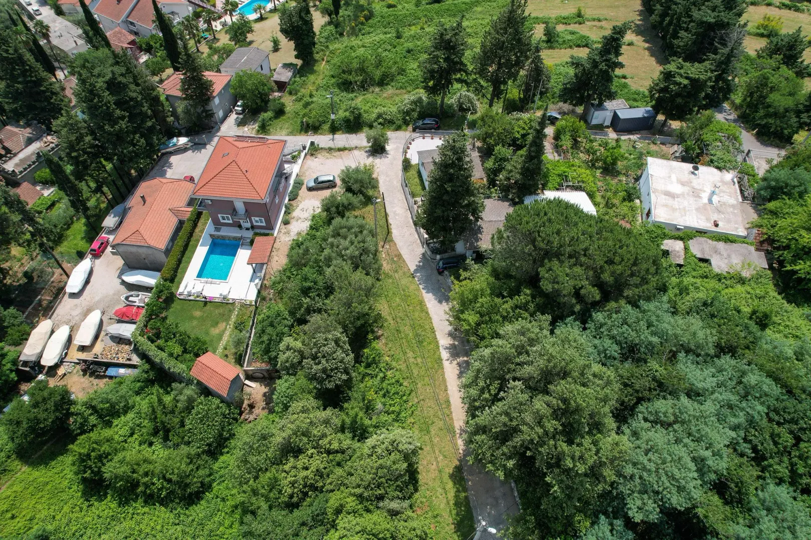 Pogled iz vazduha na imanje sa kućom, bazenom i zelenilom.