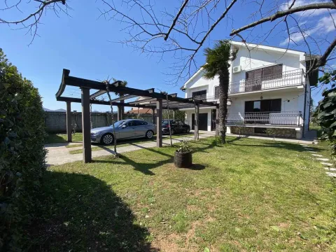 Two-story house with a landscaped yard, parking space, and wooden pergola. - image 3