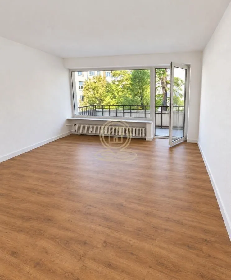 Prazna soba sa laminatom i izlazom na balkon.