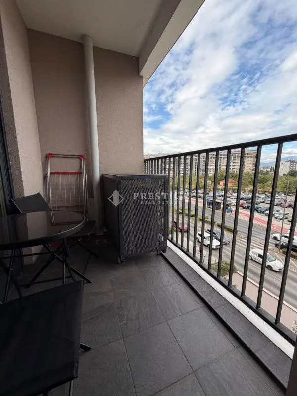 Covered balcony with seating furniture and a city view.