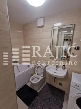 Compactly equipped bathroom with a bathtub, washbasin, and toilet. - image 5