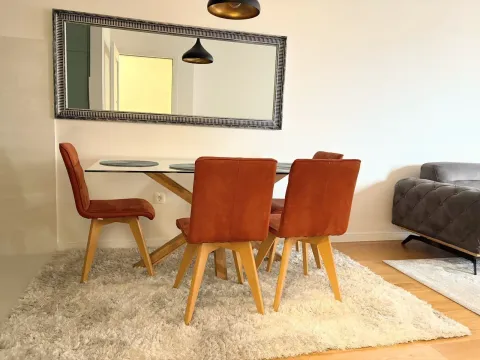 Svijetao trpezarijski prostor sa modernim stolicama i velikim ogledalom na zidu. - image 3