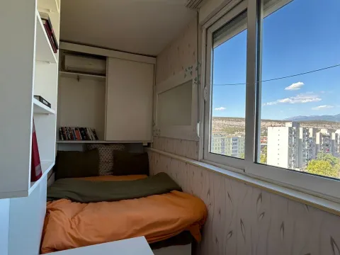 Small bedroom with a bed and a large window overlooking the city. - image 4