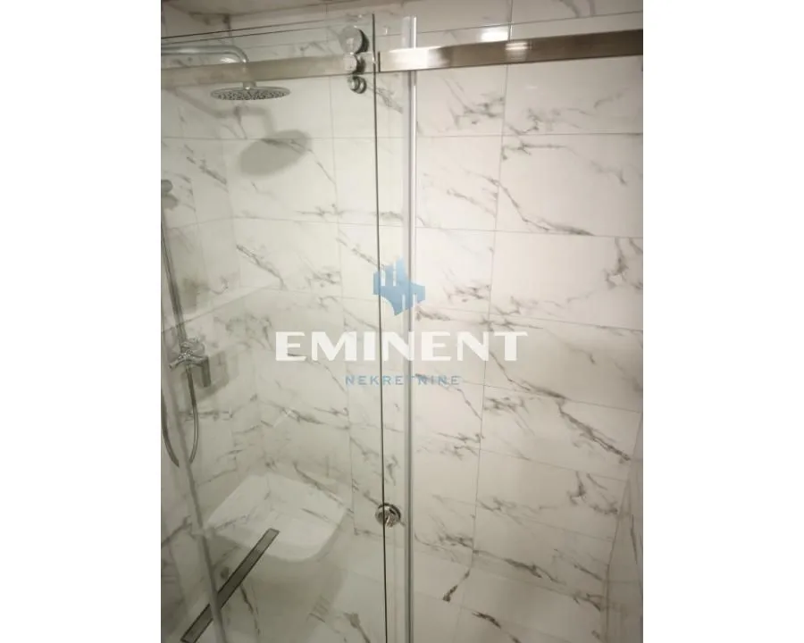 Modern shower cabin with marble tiles and a glass screen.