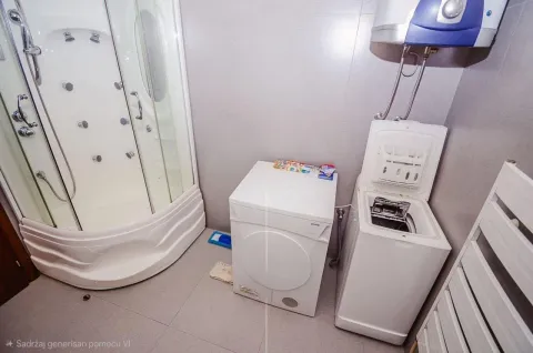 Bathroom equipped with a shower cabin, water heater, and washing and drying machines. - image 11
