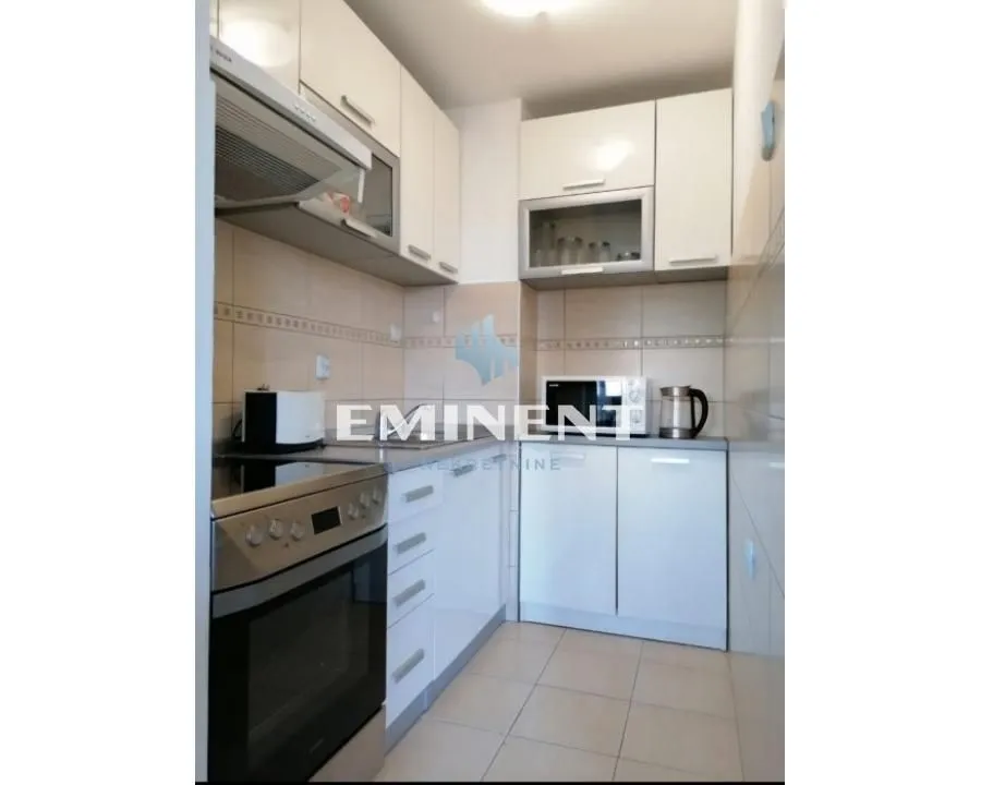 Small bright kitchen with white units and built-in kitchen appliances.
