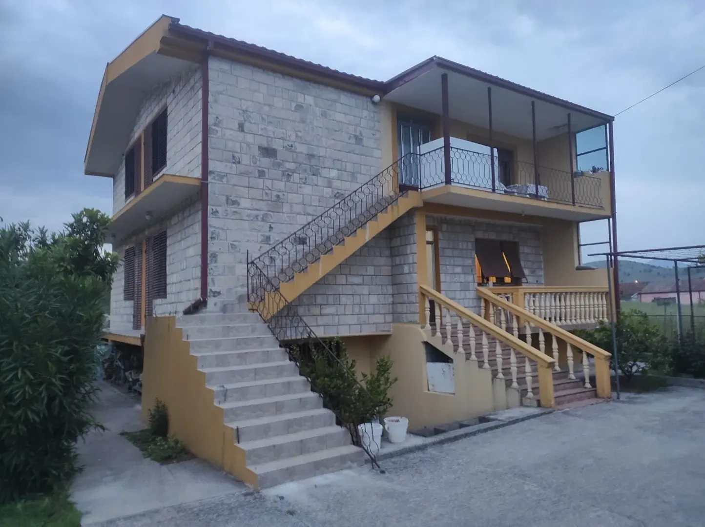 Two-story house with a stone facade and external stairs.