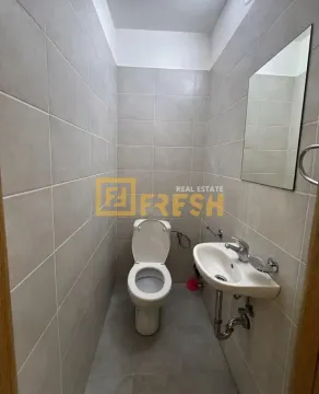 Small bathroom tiled in grey with a toilet, washbasin, and mirror. - image 5