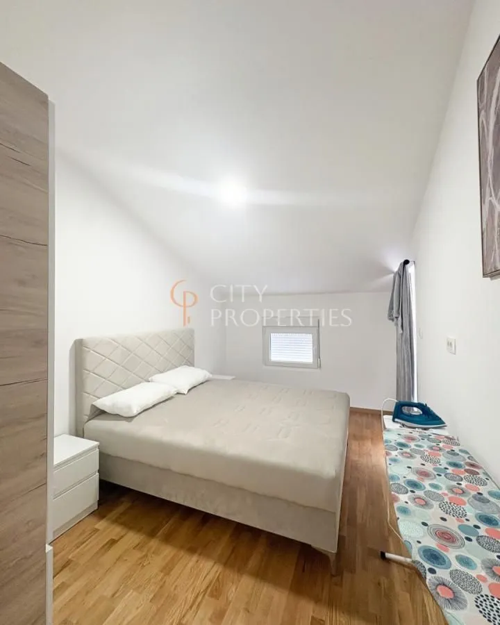 Furnished bedroom with a double bed under a sloped ceiling.