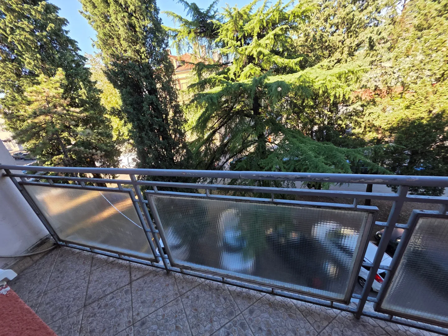 Balcony with a metal railing and a view of trees.
