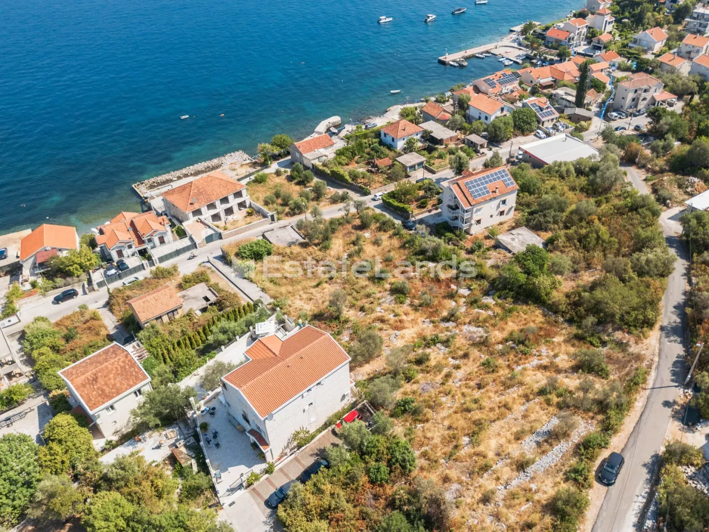 Pogled iz vazduha na priobalno naselje i okolne kućе uz more.
