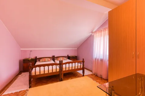 Spavaća soba sa dva drvena kreveta, roze zidovima i garderoberom. - image 6