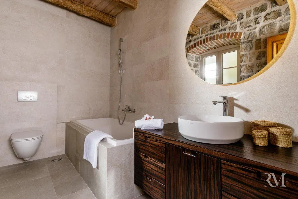 Modernly equipped bathroom with a bathtub, washbasin, and wooden elements.