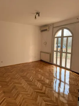 An empty room with polished parquet flooring and a large balcony door. - image 12