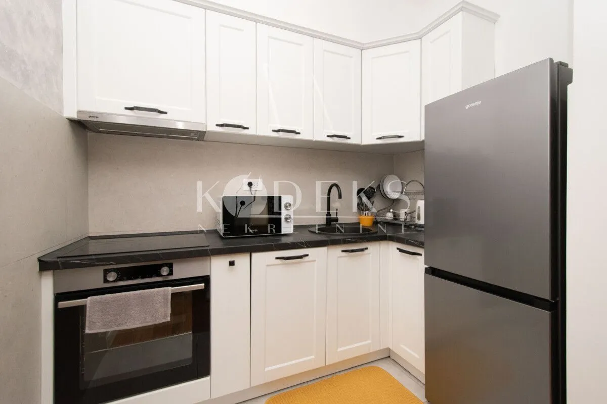 Smaller kitchen with white cabinets and a corner refrigerator.
