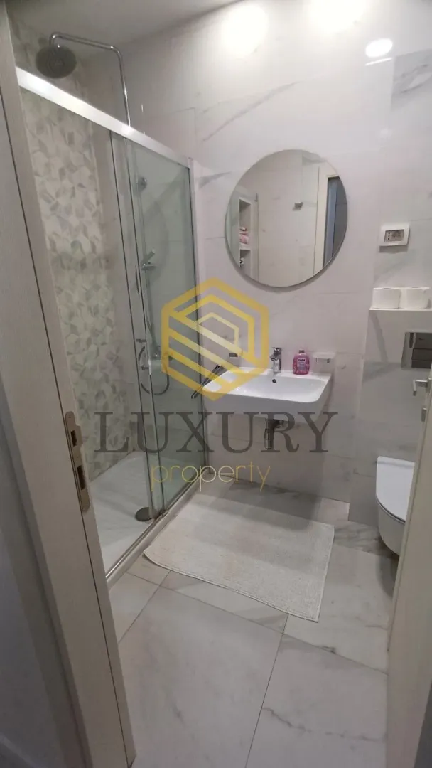 Modern bathroom with a shower cabin, washbasin, and toilet.
