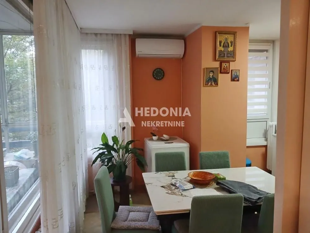 Trpezarija sa stolom, stolicama i narandžastim zidom u stanu.