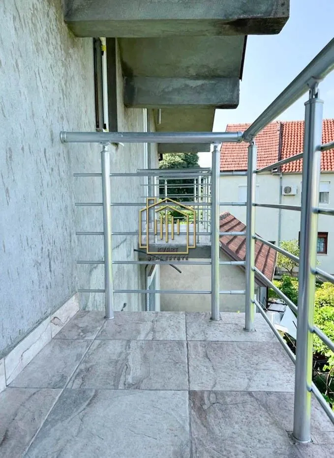 Pogled sa popločane terase sa metalnom ogradom.