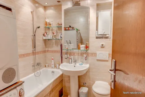 Small bathroom with a bathtub, washbasin, toilet, and washing machine. - image 18