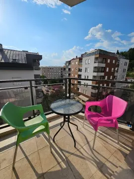 Namješten balkon sa stolom i dvije stolice i pogledom na grad. - image 9