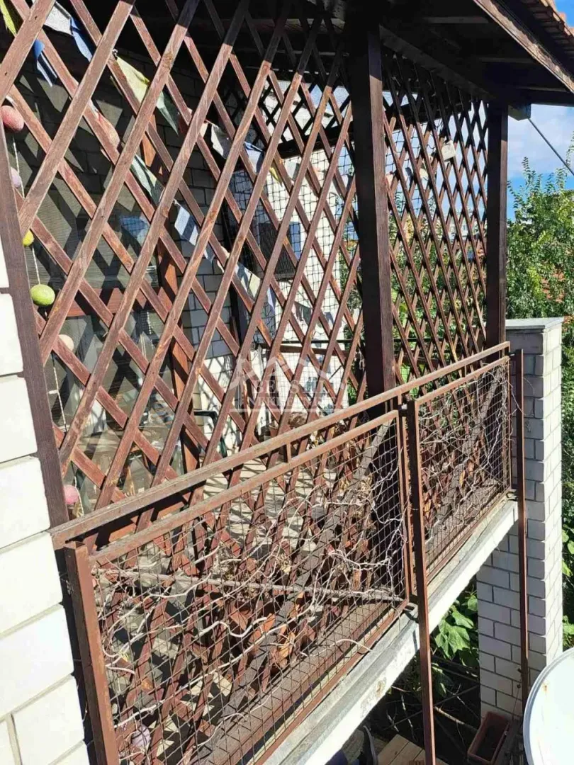 Natkriveni balkon sa drvenom rešetkom i ogradom.