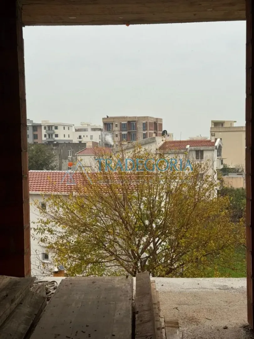 Pogled sa prozora nekretnine na okolne zgrade i drveće.