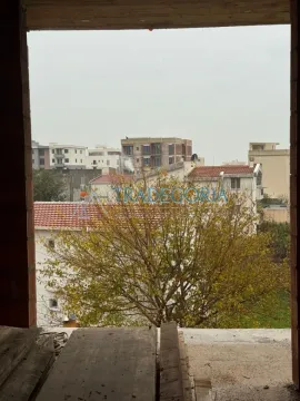 Pogled sa prozora nekretnine na okolne zgrade i drveće. - image 8