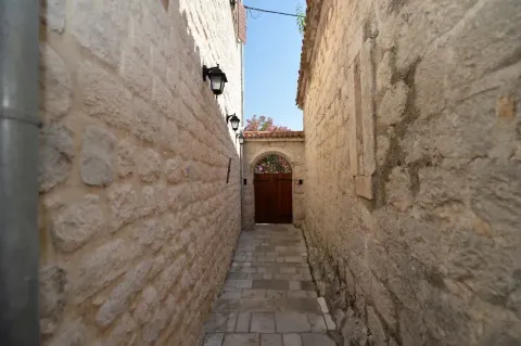 A narrow alleyway between stone walls with a paved floor and a wooden gate at the end. - image 6