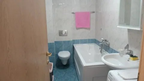A simple bathroom with a bathtub, sink, and toilet in blue and white tones. - image 9